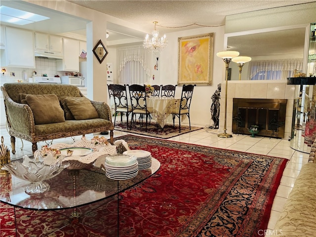 living room featuring a textured ceiling, light tile patterned floors, a tile fireplace, and a notable chandelier