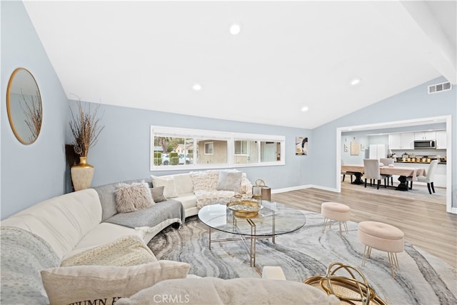 living room with vaulted ceiling with beams and light hardwood / wood-style floors