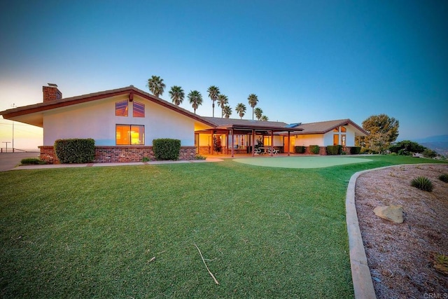 back house at dusk with a yard and a patio