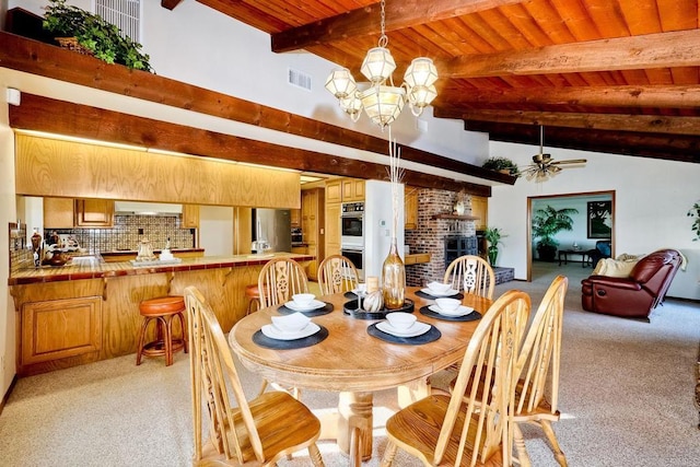 dining area with ceiling fan with notable chandelier, wooden ceiling, a brick fireplace, and light colored carpet