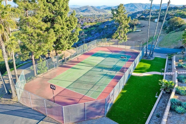 view of tennis court with a yard and a mountain view