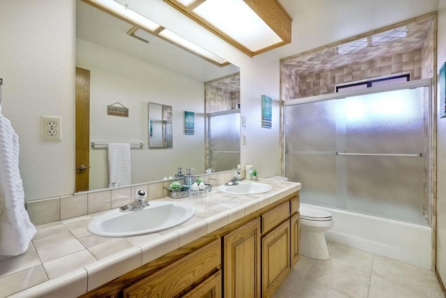 full bathroom featuring vanity, combined bath / shower with glass door, toilet, and tile patterned flooring