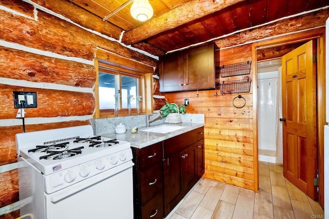 kitchen with wood ceiling, beam ceiling, wooden walls, sink, and white gas range oven