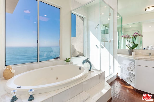 bathroom with a water view, hardwood / wood-style floors, vanity, and plus walk in shower