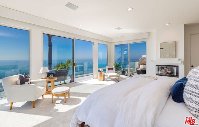 bedroom featuring a water view, multiple windows, light colored carpet, and access to exterior