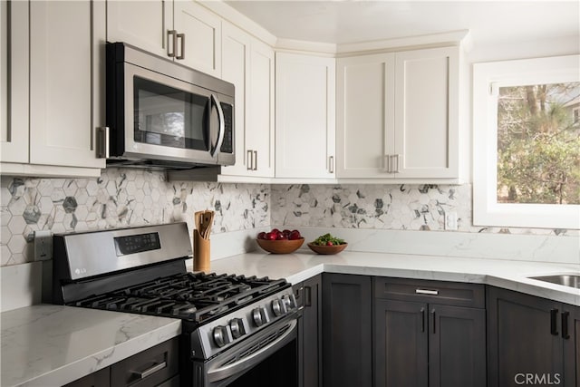 kitchen featuring stainless steel appliances, light stone countertops, and white cabinets