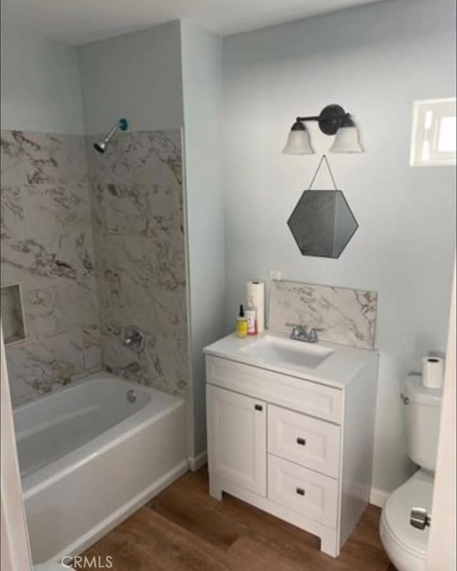 full bathroom with hardwood / wood-style floors, vanity, shower / bath combination, and toilet