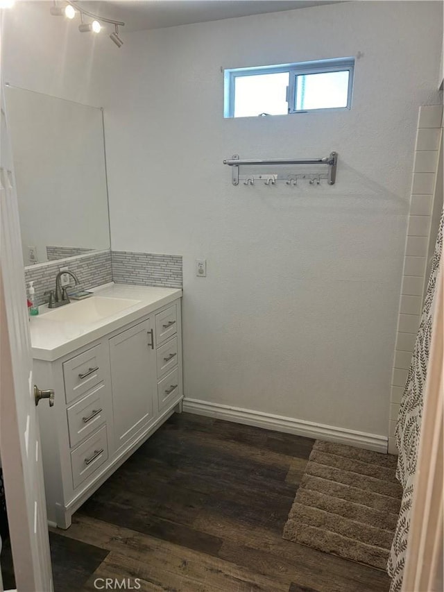 bathroom featuring wood-type flooring, vanity, and backsplash