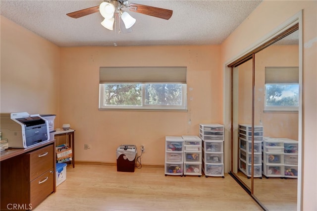 office with a textured ceiling, light hardwood / wood-style floors, and ceiling fan