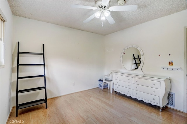 bedroom featuring ceiling fan, light hardwood / wood-style flooring, and a textured ceiling