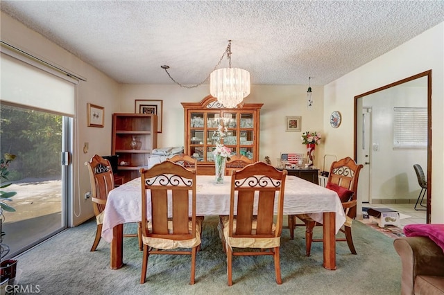 dining space with a chandelier, a textured ceiling, and carpet floors