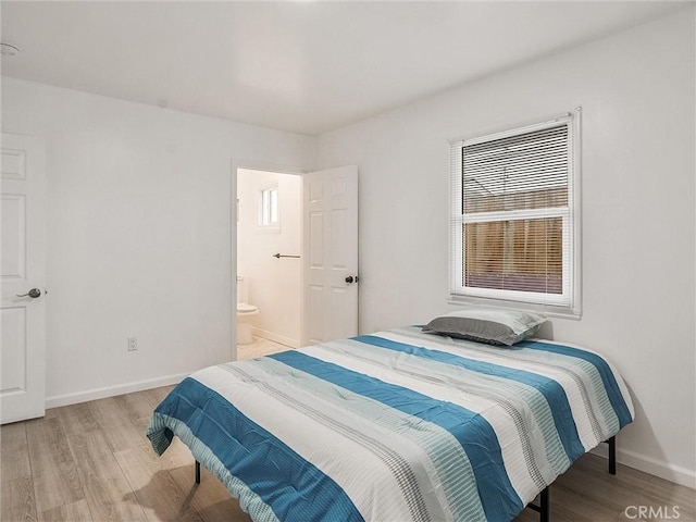 bedroom with connected bathroom and light wood-type flooring