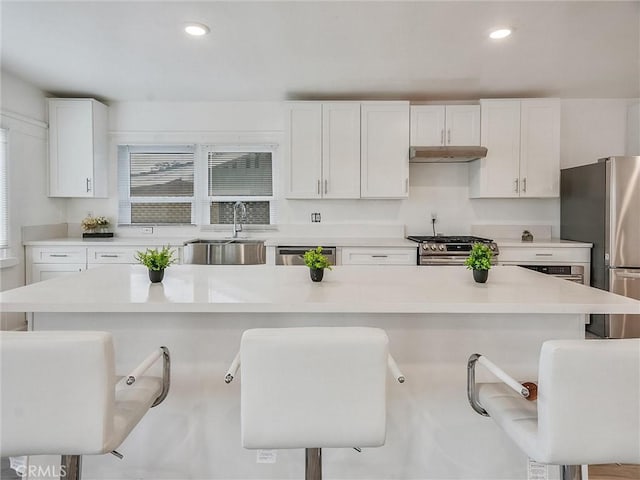 kitchen featuring a kitchen island, sink, white cabinetry, a kitchen breakfast bar, and stainless steel appliances