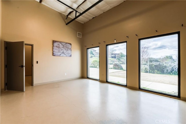 unfurnished room with concrete floors and a high ceiling