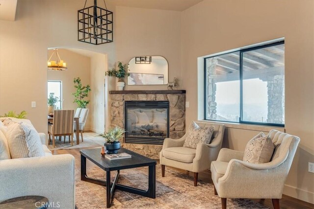 sitting room featuring a chandelier, light wood-type flooring, and a stone fireplace