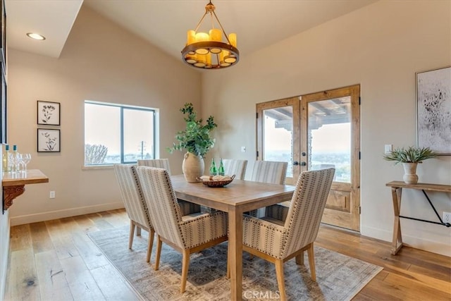 dining area with plenty of natural light, light wood-type flooring, high vaulted ceiling, and french doors