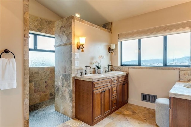 bathroom featuring a tile shower, plenty of natural light, and vanity