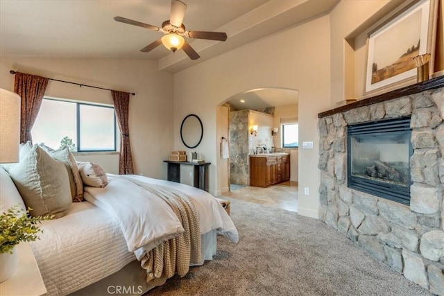 bedroom featuring multiple windows, light carpet, ensuite bathroom, and lofted ceiling