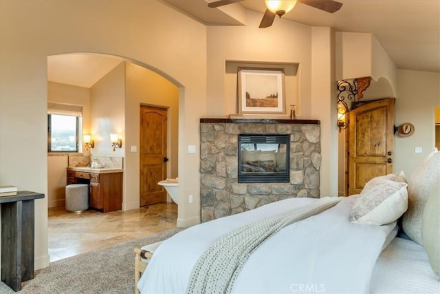 bedroom with ceiling fan, a fireplace, and ensuite bathroom