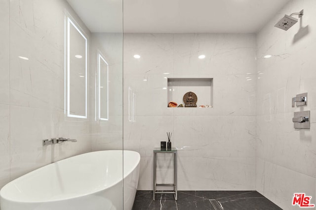 bathroom with a tub to relax in and tile walls