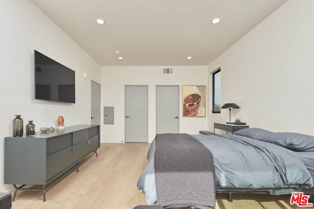 bedroom with electric panel and light wood-type flooring