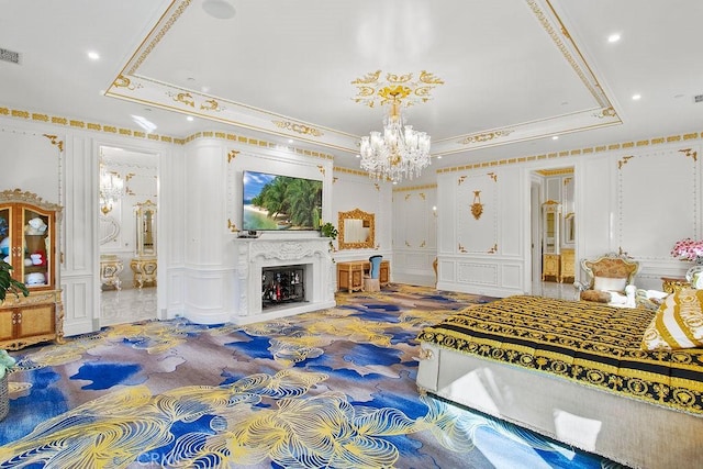 bedroom with crown molding, an inviting chandelier, a fireplace, and a tray ceiling