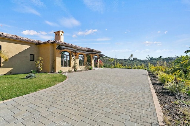 exterior space featuring decorative driveway and a yard