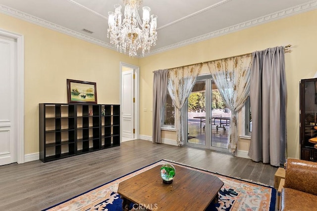 living room featuring baseboards, visible vents, wood finished floors, crown molding, and a notable chandelier