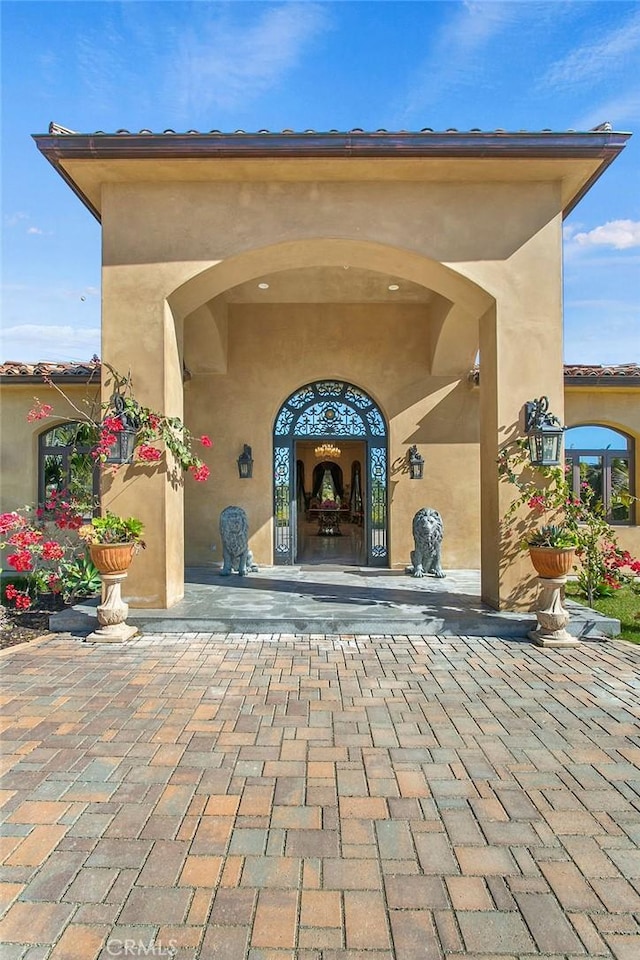 view of exterior entry featuring stucco siding and a patio