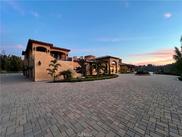 mediterranean / spanish-style home with decorative driveway, a tile roof, and stucco siding