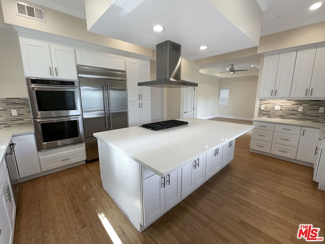 kitchen with wall chimney exhaust hood, a center island, white cabinetry, and appliances with stainless steel finishes