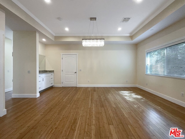 interior space featuring a tray ceiling, a chandelier, and hardwood / wood-style flooring