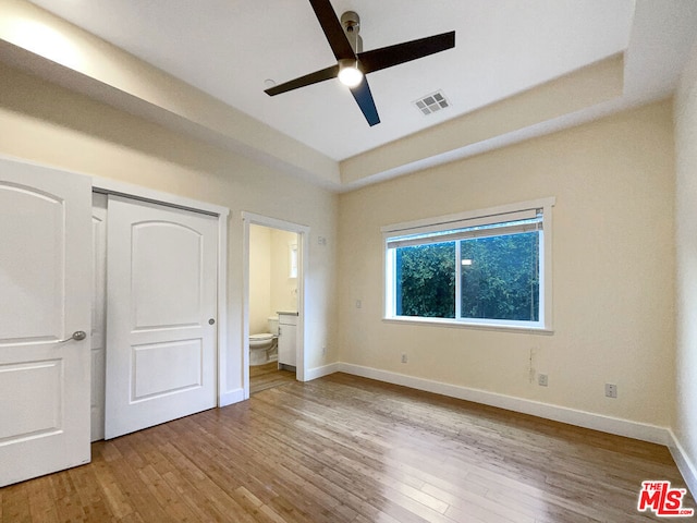 unfurnished bedroom with connected bathroom, ceiling fan, and light hardwood / wood-style floors