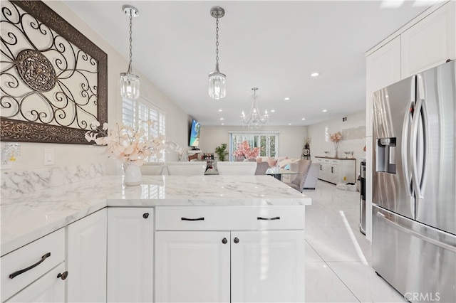 kitchen with light stone countertops, white cabinetry, stainless steel refrigerator with ice dispenser, and plenty of natural light