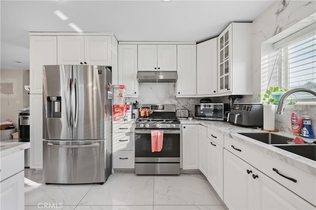 kitchen featuring white cabinets, tasteful backsplash, appliances with stainless steel finishes, light stone countertops, and sink