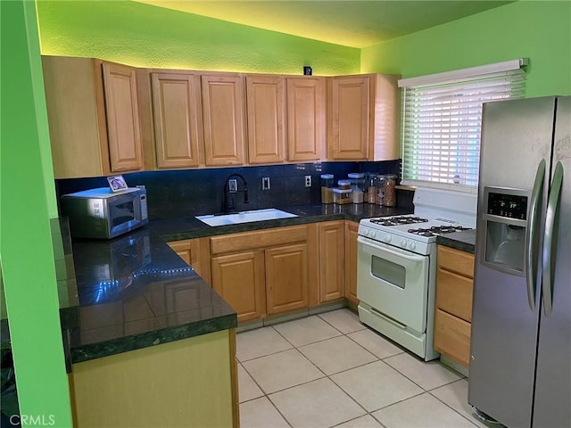 kitchen featuring tasteful backsplash, sink, light tile patterned floors, and stainless steel appliances