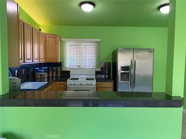 kitchen featuring stainless steel refrigerator with ice dispenser, gas range gas stove, and sink