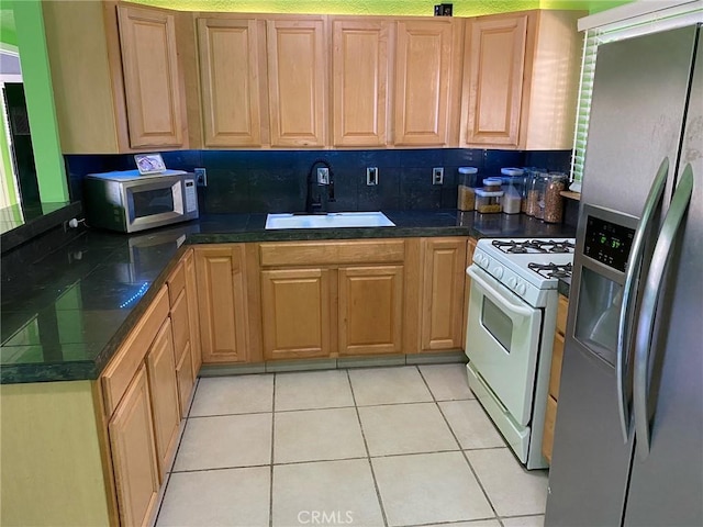 kitchen with backsplash, sink, light tile patterned floors, and appliances with stainless steel finishes