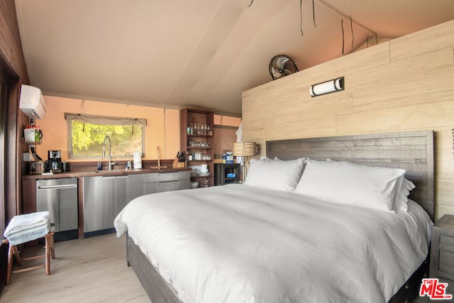 bedroom featuring lofted ceiling, sink, light hardwood / wood-style flooring, and a wall mounted air conditioner