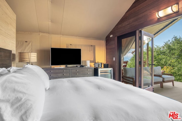 bedroom with high vaulted ceiling, wooden walls, and access to exterior