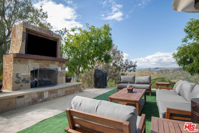 view of patio / terrace featuring a mountain view and an outdoor living space with a fireplace