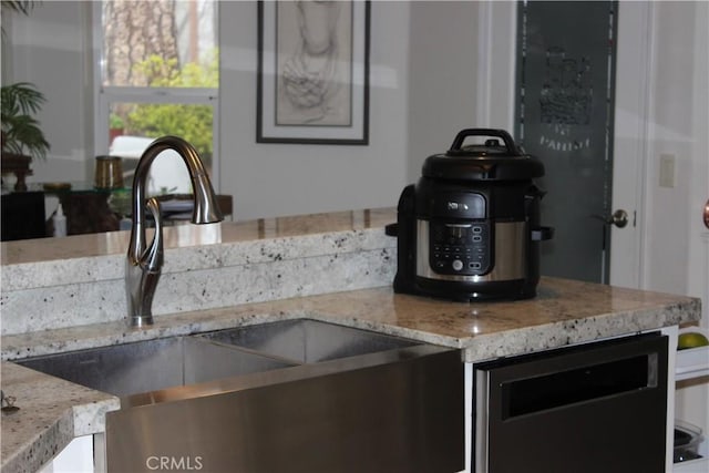 kitchen with light stone counters, sink, and beverage cooler