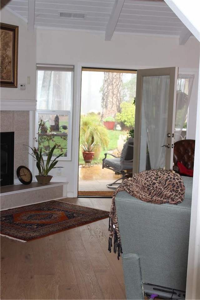 doorway to outside featuring beamed ceiling, a tile fireplace, hardwood / wood-style flooring, and wood ceiling