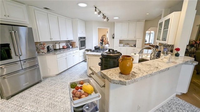 kitchen featuring white cabinetry, appliances with stainless steel finishes, a center island, and light stone counters