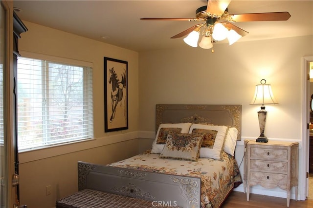 bedroom with ceiling fan, wood-type flooring, and multiple windows