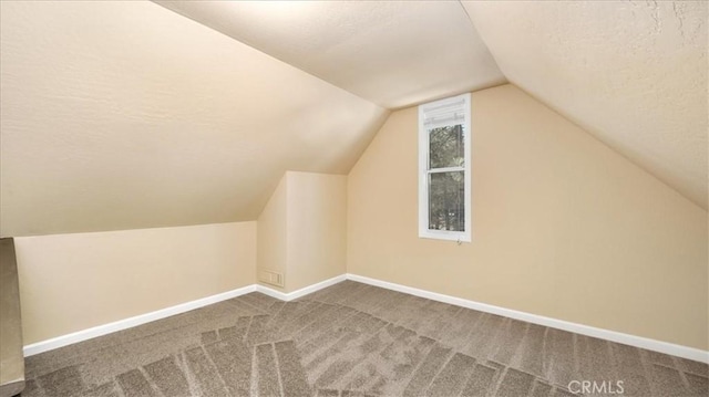 additional living space featuring lofted ceiling, carpet, and a textured ceiling