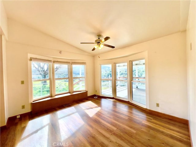 unfurnished room with lofted ceiling, ceiling fan, dark hardwood / wood-style flooring, and a healthy amount of sunlight