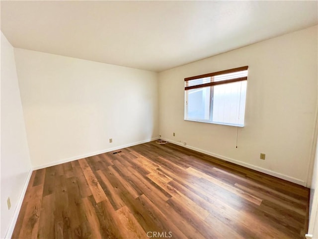 unfurnished room with dark hardwood / wood-style flooring