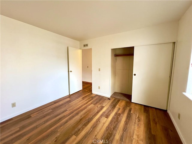 unfurnished bedroom with dark wood-type flooring and a closet