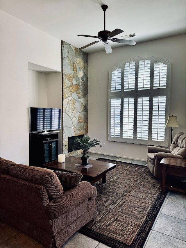 living room with ceiling fan and a stone fireplace